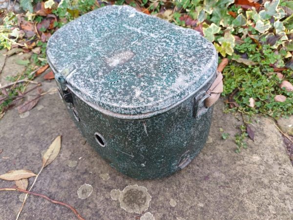 An old green cooler sitting on the ground.