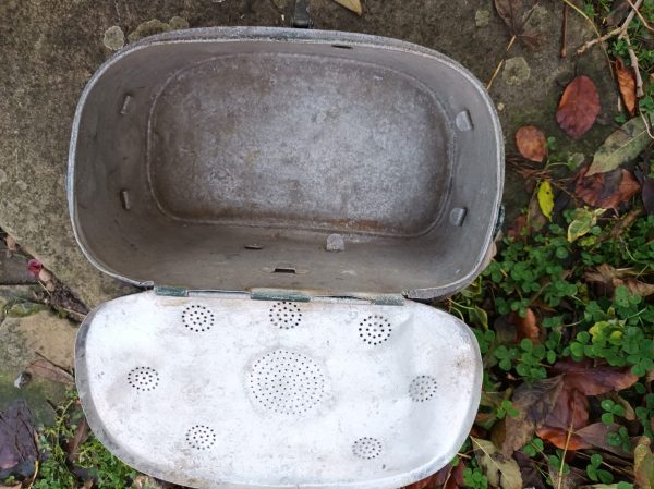 A metal trash can sitting on the ground.