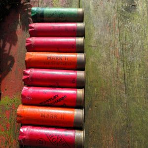 A row of Vintage Spent Shotgun Cartridges on a wooden table.