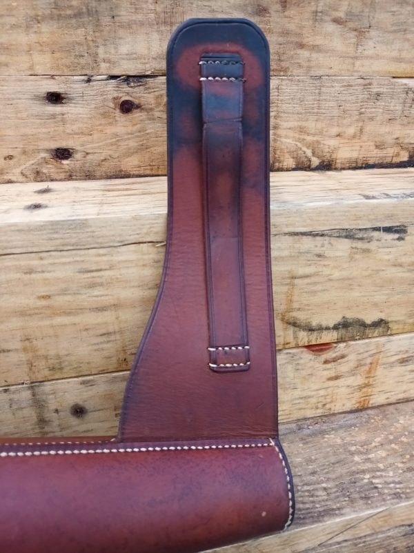 A brown leather holster hanging on a wooden wall.
