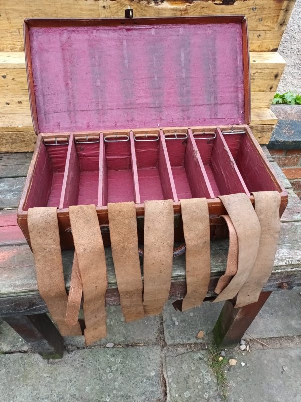 An English 19th Century Leather Cartridge Case with several compartments sitting on a wooden bench.