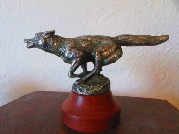 A bronze statue of a running Fox Car Mascot or Hood Ornament (USA) on a wooden base, serving as a running fox car mascot.