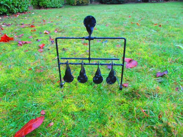 An Antique Cast Iron Shooting Target in a grassy area, serving as an antique decorative piece.